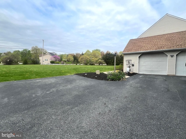 view of side of home with a yard, a garage, and aphalt driveway