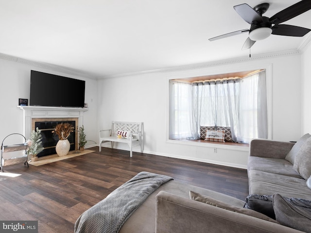 living room featuring ornamental molding, wood finished floors, baseboards, ceiling fan, and a tile fireplace