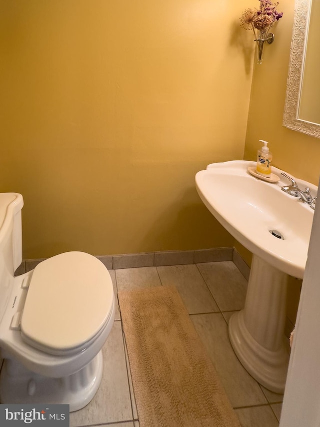 half bathroom with baseboards, tile patterned floors, and toilet