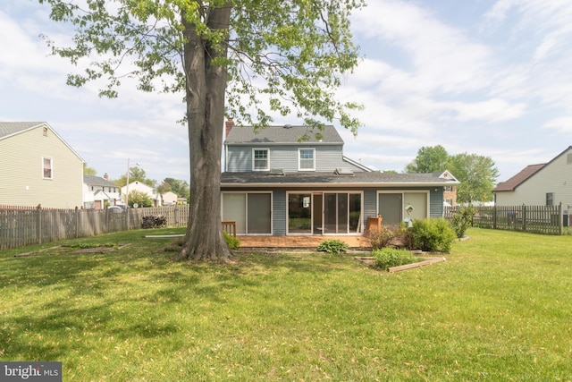 back of house featuring a lawn, a fenced backyard, and a chimney