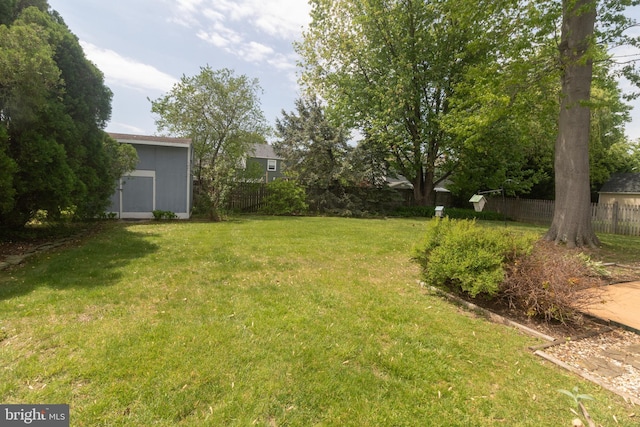 view of yard featuring fence and an outbuilding
