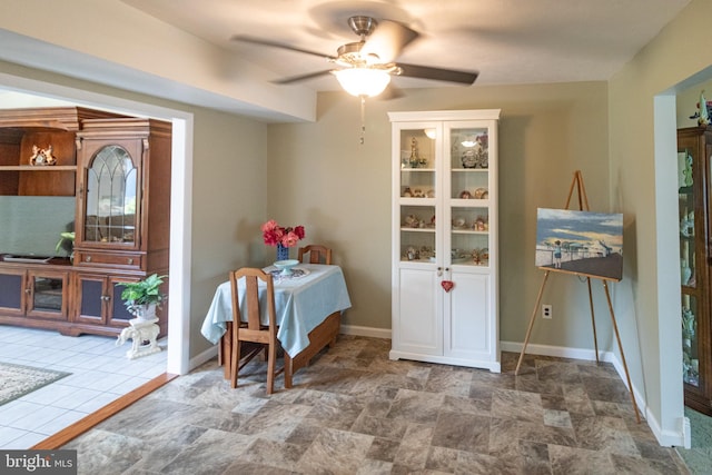 dining room with baseboards, ceiling fan, and stone finish floor