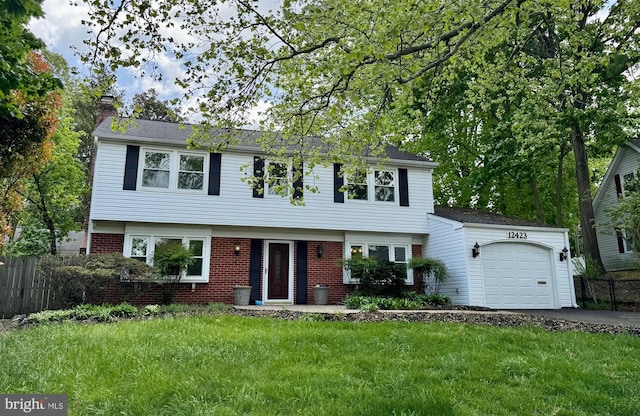 colonial house with a front lawn, fence, a chimney, brick siding, and an attached garage