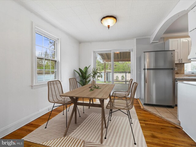 dining room featuring light wood-style floors, arched walkways, and a wealth of natural light