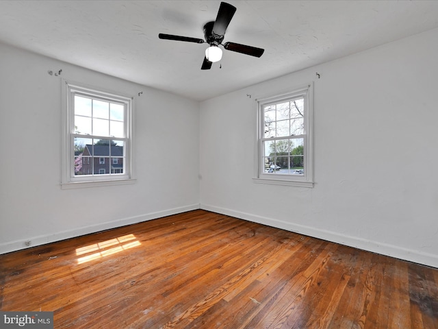 empty room featuring baseboards, a wealth of natural light, and hardwood / wood-style floors