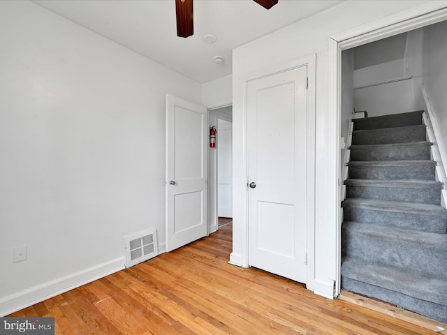 stairs featuring baseboards, ceiling fan, visible vents, and wood finished floors