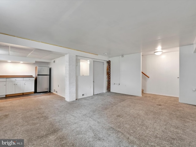finished basement featuring freestanding refrigerator, light carpet, and stairs