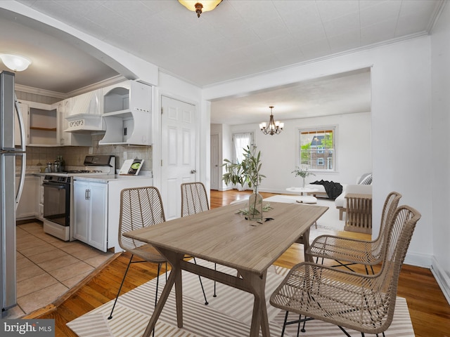 dining space with baseboards, a chandelier, ornamental molding, and light wood finished floors