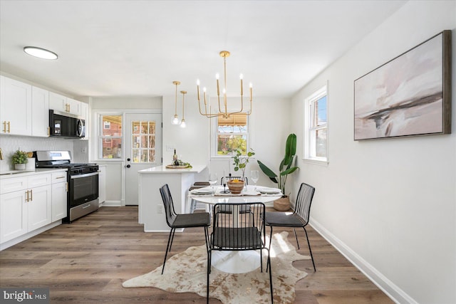 dining area with an inviting chandelier, baseboards, and light wood-type flooring