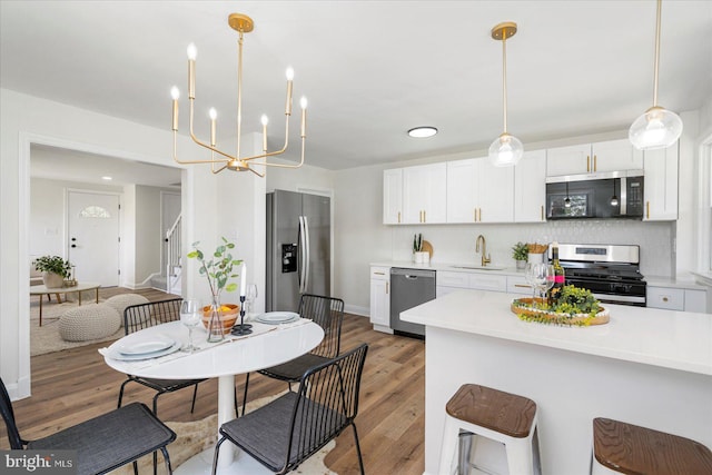 577 Lucia Ave, Baltimore, MD 21229 - kitchen with appliances with stainless steel finishes, a sink, light countertops, a notable chandelier, and light wood-style floors