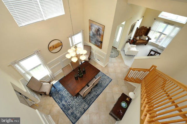 living area featuring a high ceiling, an inviting chandelier, tile patterned flooring, and a decorative wall