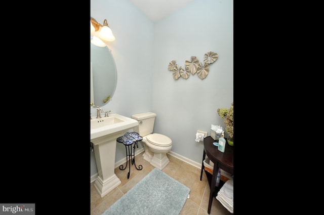 bathroom featuring a sink, tile patterned floors, baseboards, and toilet