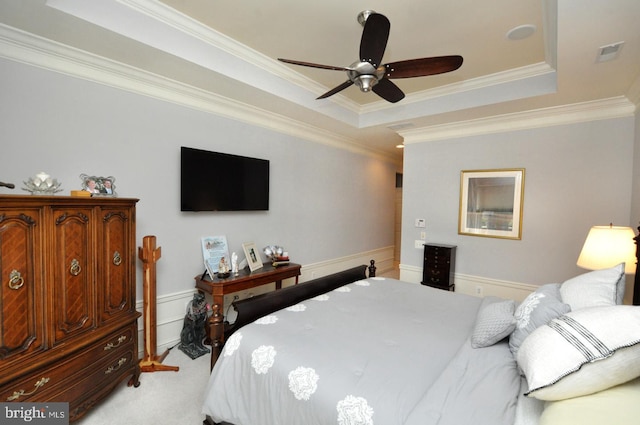 bedroom featuring visible vents, crown molding, a tray ceiling, and light carpet