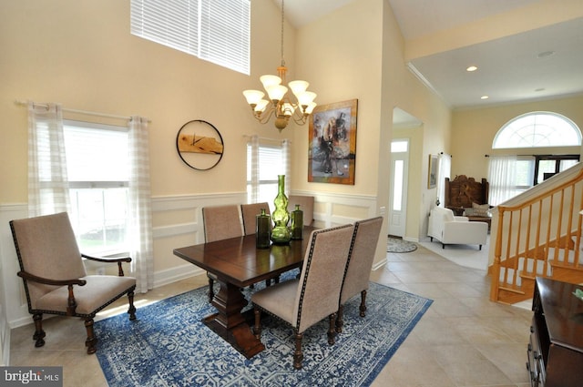 dining area with light tile patterned floors, a wainscoted wall, stairway, and a notable chandelier