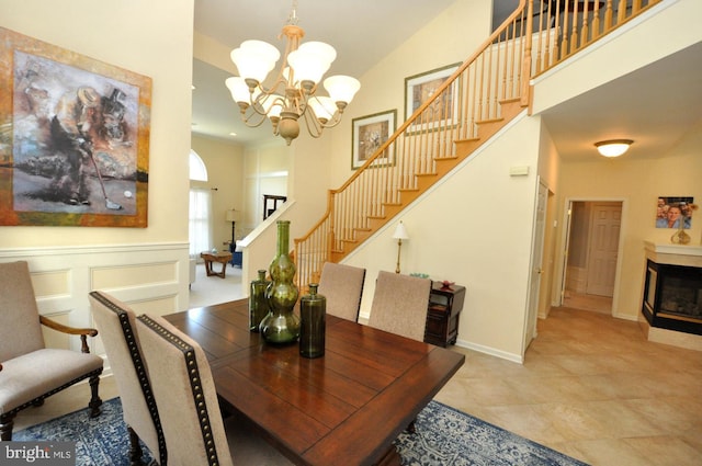dining space with baseboards, a high ceiling, a chandelier, and stairway