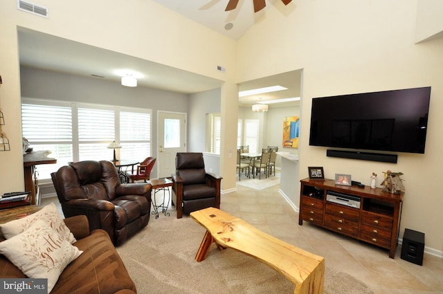 living room featuring visible vents, baseboards, ceiling fan, and a high ceiling