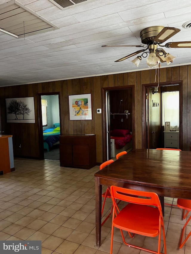 dining room featuring wooden walls, ceiling fan, and visible vents
