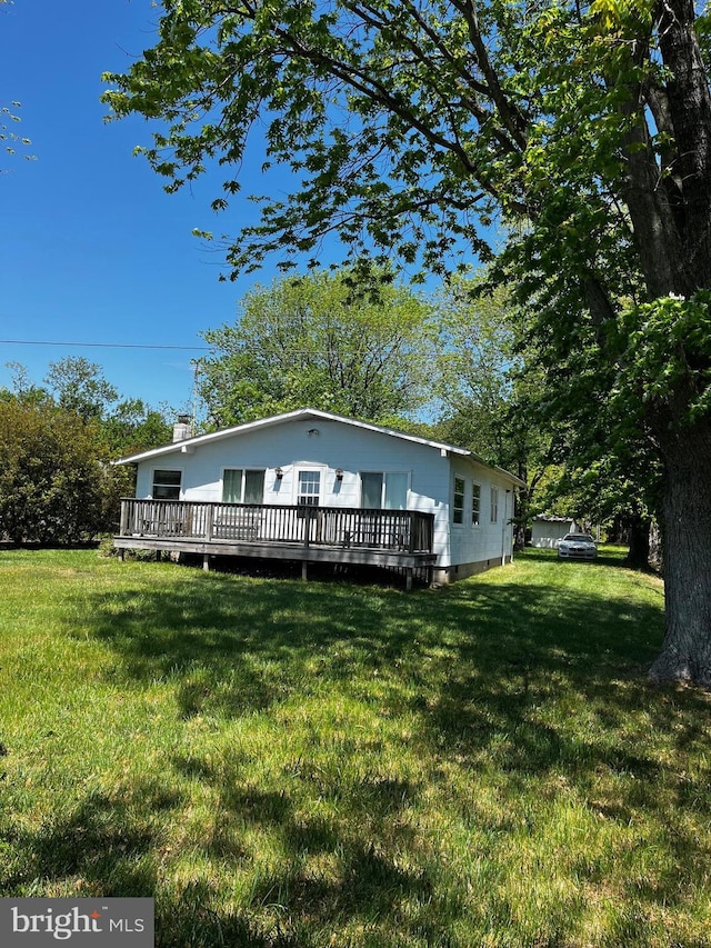 rear view of property with a wooden deck and a yard