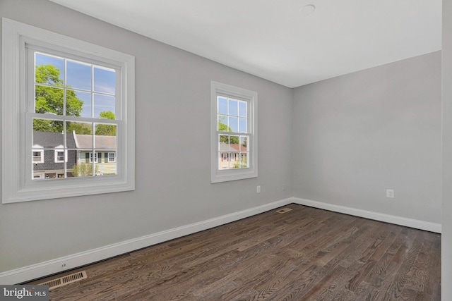 spare room featuring baseboards, visible vents, and dark wood-type flooring
