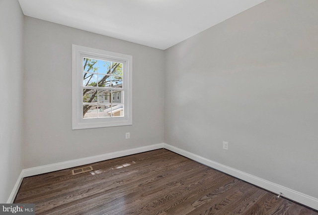 unfurnished room featuring baseboards and dark wood finished floors