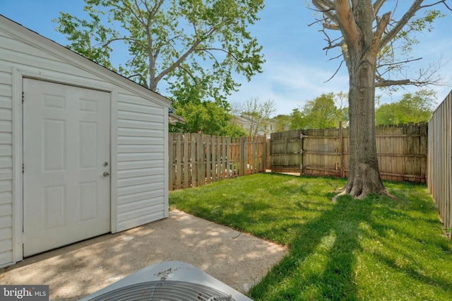 view of yard featuring an outdoor structure, a fenced backyard, and a storage unit