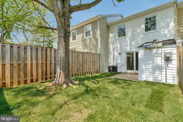 rear view of house featuring central air condition unit, a lawn, and fence