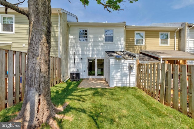 rear view of property with a fenced backyard, central AC, and a yard