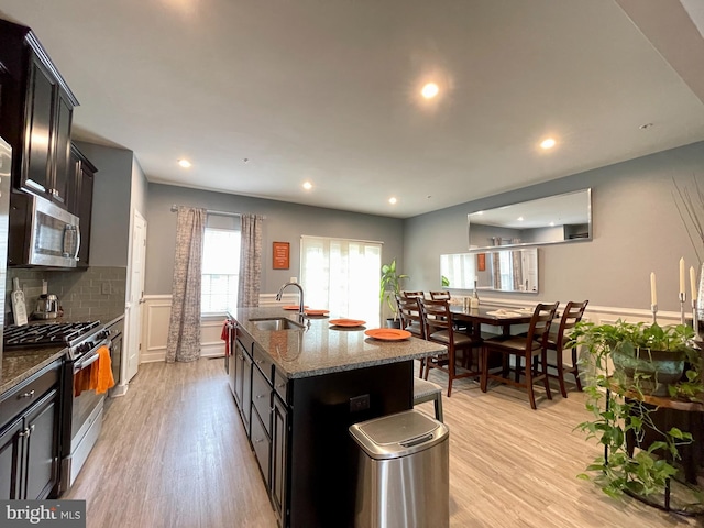 14503 Hunts Farm Rd, Brandywine, MD 20613 - kitchen featuring stainless steel appliances, wainscoting, light wood-type flooring, dark stone countertops, and an island with sink