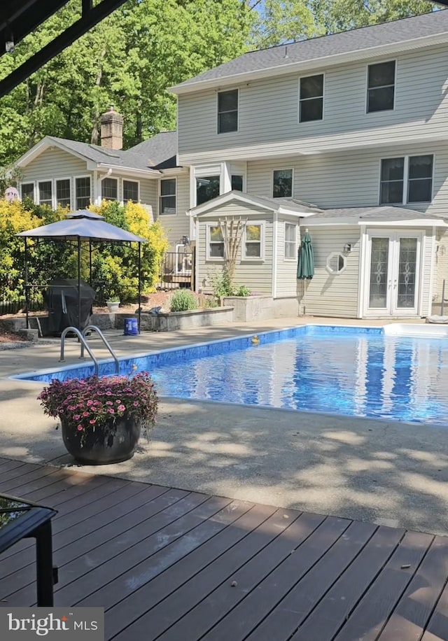 outdoor pool with french doors and a deck