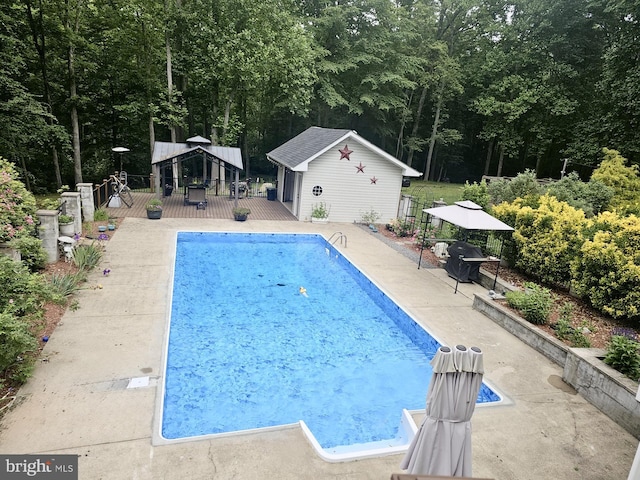 view of swimming pool with a gazebo, a deck, a fenced in pool, an outbuilding, and a patio area