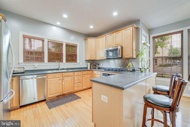 11559 Cavalier Landing Ct, Fairfax, VA 22030 - kitchen with appliances with stainless steel finishes, light brown cabinetry, a sink, dark countertops, and a peninsula