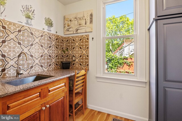 541 Madison Ave, York, PA 17404 - kitchen with light stone countertops, light wood-style floors, brown cabinets, tasteful backsplash, and a sink