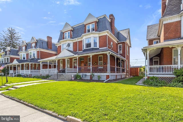 541 Madison Ave, York, PA 17404 - victorian home featuring covered porch, a chimney, a front lawn, and brick siding