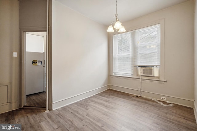 unfurnished dining area with visible vents, wood finished floors, baseboards, cooling unit, and a chandelier
