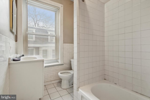 bathroom with vanity, toilet, a washtub, tile walls, and tile patterned floors