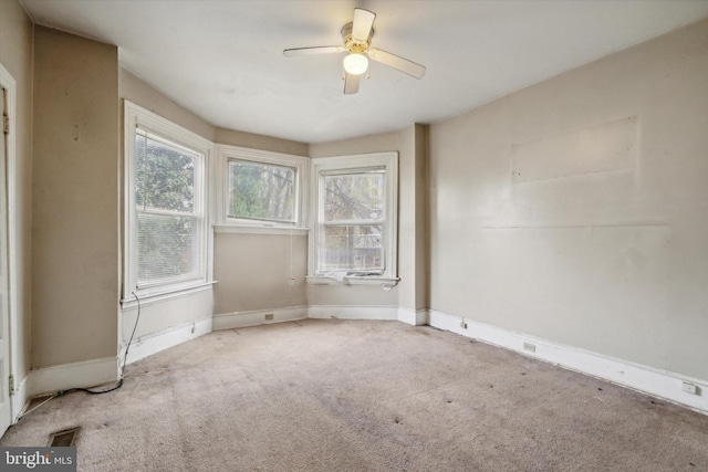 carpeted spare room featuring baseboards and a ceiling fan