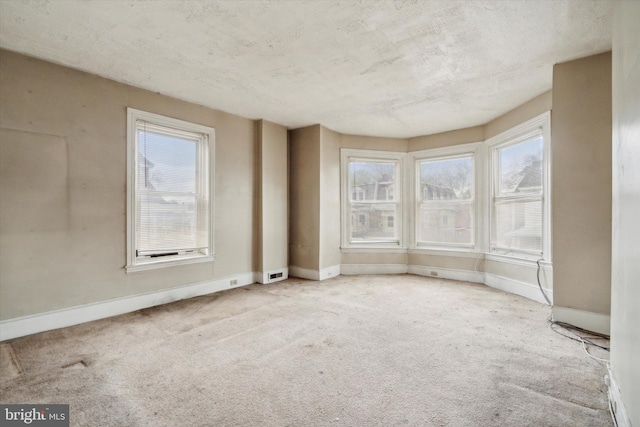 spare room with carpet flooring, baseboards, and visible vents