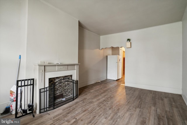 unfurnished living room with baseboards, wood finished floors, and a fireplace