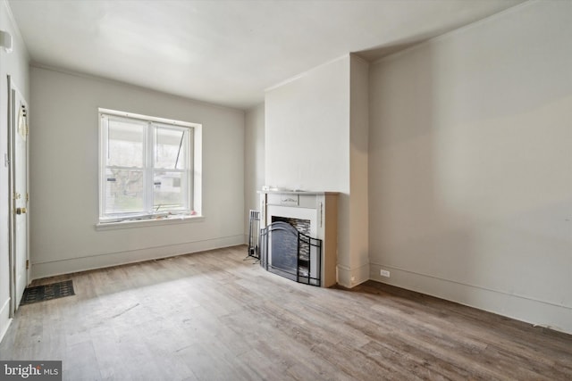 unfurnished living room with visible vents, baseboards, wood finished floors, and a fireplace