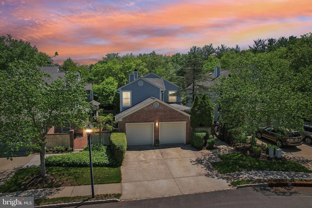 view of front of home with brick siding, concrete driveway, a garage, and fence
