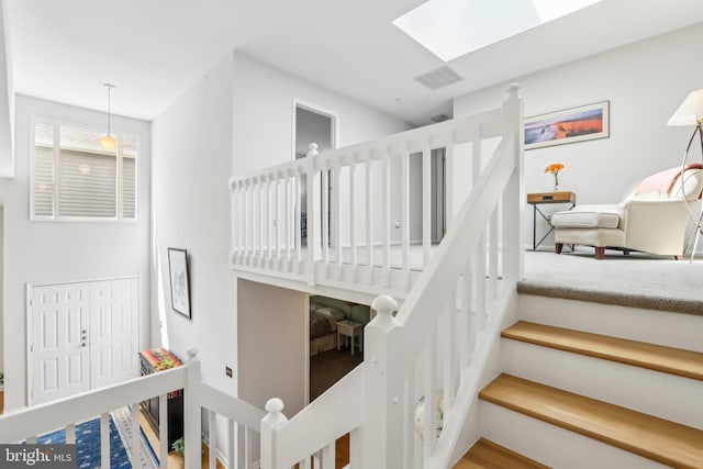 stairs featuring a skylight and wood finished floors