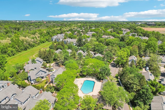 aerial perspective of suburban area with a pool and a heavily wooded area