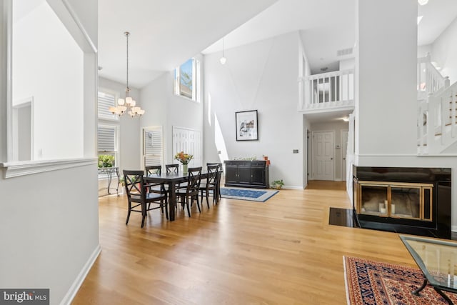 dining area featuring a towering ceiling, baseboards, plenty of natural light, a chandelier, and wood finished floors