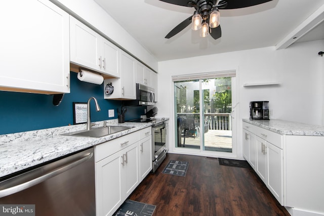 kitchen with appliances with stainless steel finishes, a sink, dark wood finished floors, a ceiling fan, and white cabinetry