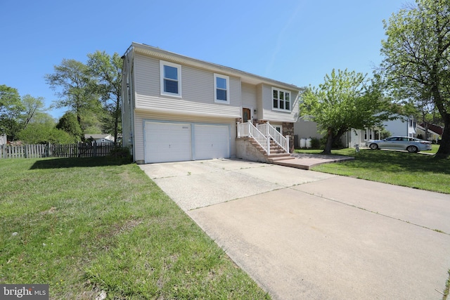split foyer home with a garage, fence, concrete driveway, and a front lawn