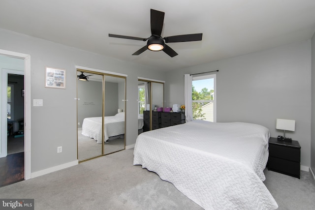 carpeted bedroom featuring baseboards, multiple closets, and ceiling fan