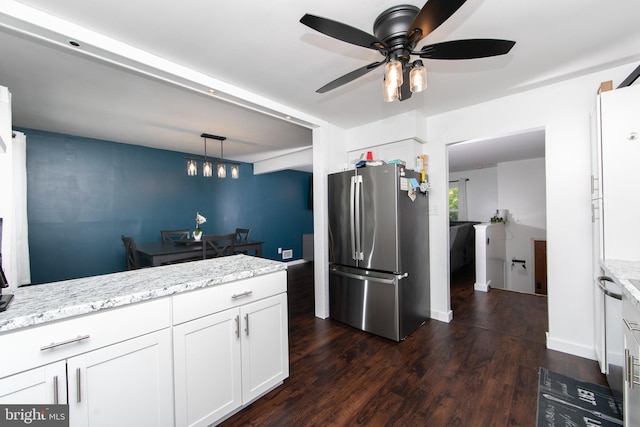 kitchen featuring dark wood-style flooring, light stone countertops, ceiling fan, freestanding refrigerator, and white cabinetry