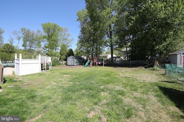 view of yard featuring a storage shed, fence, an outbuilding, and a playground