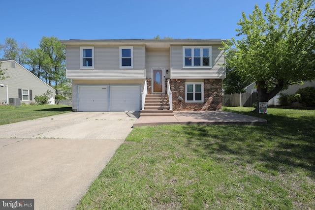 raised ranch featuring a front lawn, brick siding, central AC unit, an attached garage, and driveway
