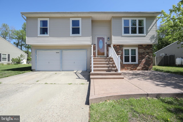 bi-level home featuring an attached garage, concrete driveway, and brick siding